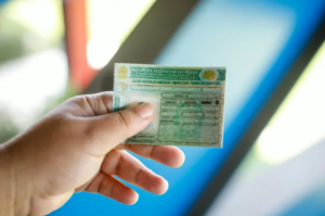 A imagem mostra uma mão segurando uma CNH D.